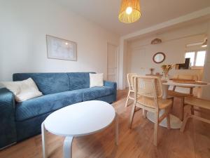 ein Wohnzimmer mit einem blauen Sofa und einem Tisch in der Unterkunft Beautiful 2 Bedroom apartment in a quiet residence in Garches