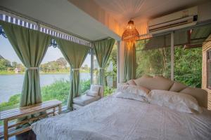 a bedroom with a bed and a view of the water at River Flow House (บ้านสายนํ้า) in Ratchaburi