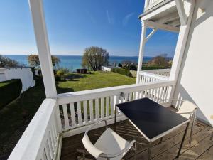 een tafel en stoelen op een veranda met de oceaan op de achtergrond bij Meerblick-Ferienwohnung - Villa Bertha s Heim in Sassnitz