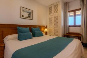 a bedroom with a large bed with blue pillows at Hotel Club Sunway Punta Prima in Es Pujols