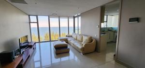 a living room with a couch and a large window at SUPER MARES_Comfortable & Cozy Apartment in Maputo