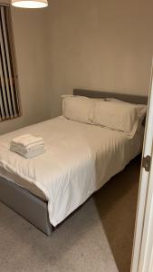 uma cama com lençóis brancos e almofadas em Luxury Flat Town Centre em Reading