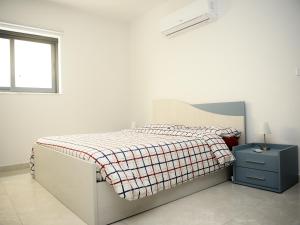 1 dormitorio blanco con 1 cama con manta a cuadros en Seaview-CasadiAlfio-Qawra, en St Paul's Bay