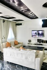 uma sala de estar com um sofá branco e uma televisão de ecrã plano em The Hidden Gem Wuye em Abuja