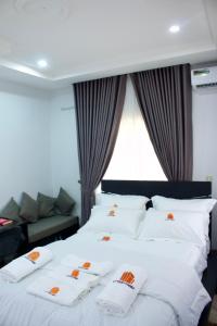 um quarto com uma cama com almofadas brancas e um sofá em The Hidden Gem Wuye em Abuja