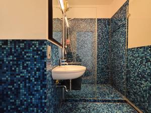 a bathroom with a sink and a shower with blue tiles at Meerblick-Ferienwohnung - Villa Bertha s Heim in Sassnitz +1 photo