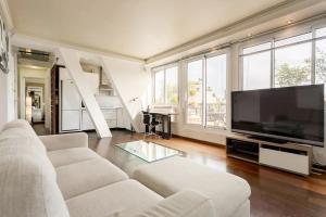 a living room with a white couch and a flat screen tv at Appartement Grande Terrasse Vue Tour Eiffel in Paris