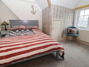 um quarto com uma cama com bandeira americana e uma cadeira azul em Stone's Throw em Budleigh Salterton