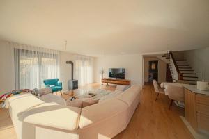 a living room with a large white couch and chairs at Bujtina e Gjyshes in Peje