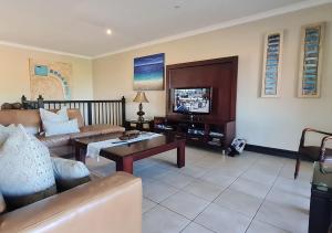 a living room with a couch and a tv at Zimbali KJ01 4 Bedroom Home in Ballito