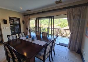 a dining room with a table and chairs and a balcony at Zimbali KJ01 4 Bedroom Home in Ballito