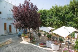 eine Terrasse mit Sonnenschirmen, Stühlen und Pflanzen in der Unterkunft Cummersa Mazzini casa tipica nel Centro storico DI Locorotondo in Locorotondo