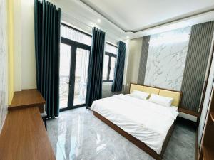 a bedroom with a large bed and large windows at TONY HOMESTAY CẦN THƠ in Can Tho