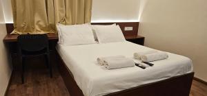 a bedroom with a bed with white sheets and towels at Chippy Inn in Chennai
