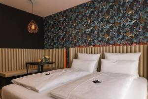 sypialnia z łóżkiem i ścianą z tapetą w obiekcie Rioca Konstanz Posto 10 w Konstancji