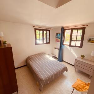 a bedroom with a bed and two windows at Villa La Louette, 100m centre-village, piscine h-sol, proche mer in Saint-Cyr-sur-Mer