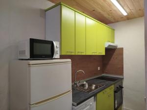 a kitchen with green cabinets and a microwave and a sink at Berrocal de Aldea en Cabo in Aldeaencabo de Escalona