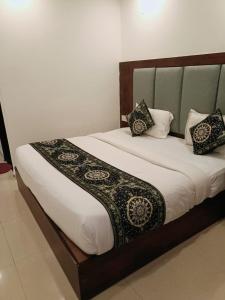 a bed with a wooden headboard and pillows on it at Hotel Ambience Dilli 37 At - Near IGI Airport in New Delhi