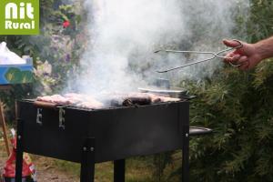 a person is cooking meat on a grill at Ca L'Estrada in Sant Esteve de Palautordera