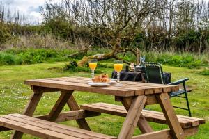 uma mesa de piquenique em madeira com dois copos de vinho em Canvas & Cabins - Orchard View em Germansweek
