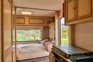 um quarto num trailer com uma cama e uma janela em Canvas & Cabins - Orchard View em Germansweek