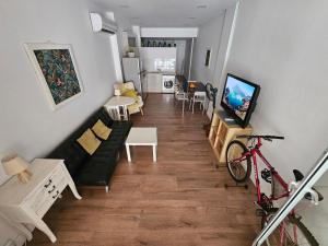 Unique Sea & City Lifestyle Studio في ليماسول: غرفة معيشة مع أريكة سوداء وتلفزيون