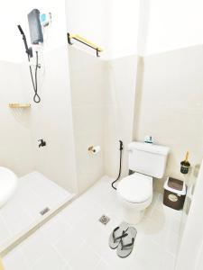 a white bathroom with a toilet and a shower at Aashvi Cozy Cabin Hostel near Mactan Airport in Pusok