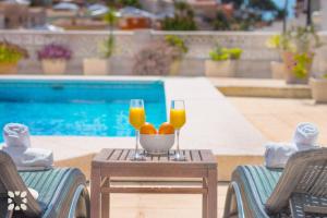dos vasos de zumo de naranja y naranjas en una mesa junto a una piscina en Villa Puerto Blanco by Abahana Villas, en La Canuta