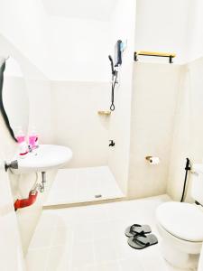 a white bathroom with a sink and a toilet at Aashvi Cozy Cabin Hostel near Mactan Airport in Pusok