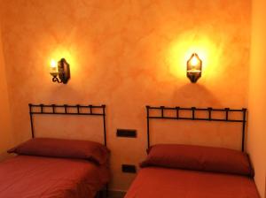 Casa Rural Sierra Vicor في Sediles: سريرين في غرفة مع أضواء على الحائط