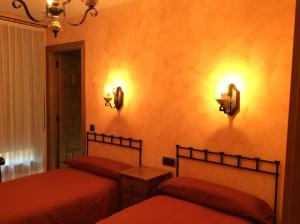 Casa Rural Sierra Vicor في Sediles: غرفة نوم بسريرين واضاءتين على الحائط