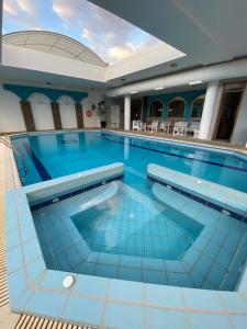 una gran piscina en un hotel con azulejos azules en Hotel Kalloni, en Volos