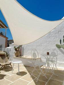 a patio with chairs and tables and a white wall at Palmieri Luxury Rooms in Gallipoli