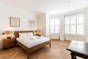 a bedroom with a bed and a table and windows at Urban Living - 2Bed 2Bath in South Kensington in London