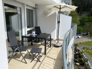 une table et des chaises noires sur un balcon avec un parasol dans l'établissement Neu!!! Ferienwohnung Mosel 106,5, à Traben-Trarbach