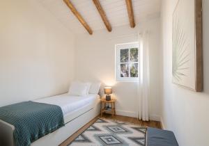 a white bedroom with a bed and a window at Descanso das Palmeiras - HOST & CHILL in Furnas