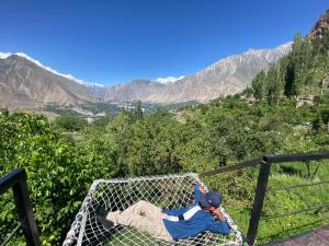 a man laying in a hammock on a mountain at Glamping Resort Hunza in Hunza