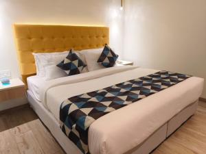 um quarto com uma cama grande e uma cabeceira amarela em World Inn Hotel em Visakhapatnam