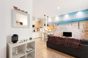 un soggiorno con divano e un dipinto di una spiaggia di Suite Jinetes a Málaga