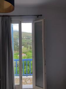 una puerta corredera de cristal con vistas a un balcón en Andros Guesthouses, en Ándros