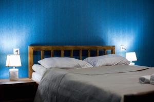 a bedroom with a bed with blue walls and two lamps at ციბენა • Tsibena in Ambrolauri