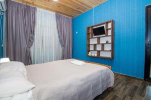 1 dormitorio con cama blanca y pared azul en ციბენა • Tsibena en Ambrolauri