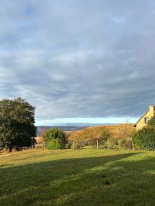 a grassy field with a house in the distance at Highlands Farm Cottage in Van Reenen