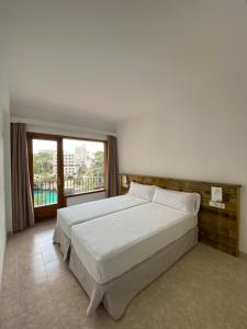 a bedroom with a large bed and a large window at Hostal Palmaria in Cala Santanyi
