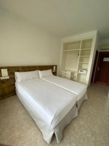 a bedroom with a large white bed in a room at Hostal Palmaria in Cala Santanyi