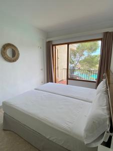 a bedroom with a large bed with a window at Hostal Palmaria in Cala Santanyi