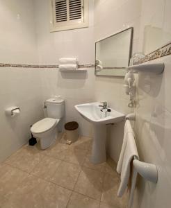 a white bathroom with a toilet and a sink at Hostal Palmaria in Cala Santanyi