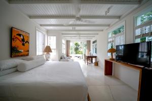 een witte slaapkamer met een groot bed en een televisie bij Bodhi Bingin in Uluwatu