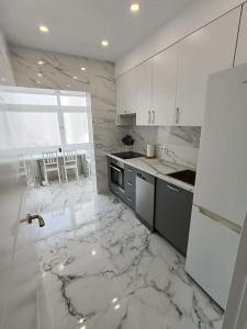 a white kitchen with marble floors and a white refrigerator at Nuevo apartamento cerca del mar in Denia