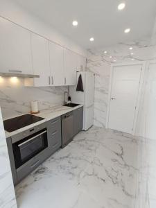 a white kitchen with marble floors and a counter top at Nuevo apartamento cerca del mar in Denia +19 photos